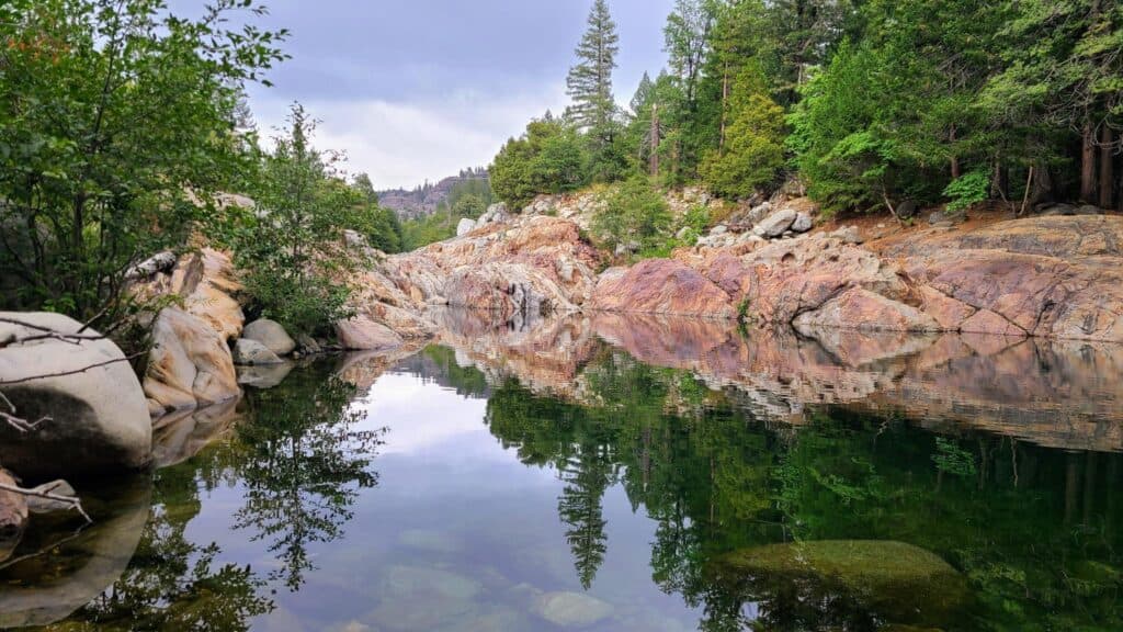 the emerald pools up close with the trees reflecting in the green clear water.