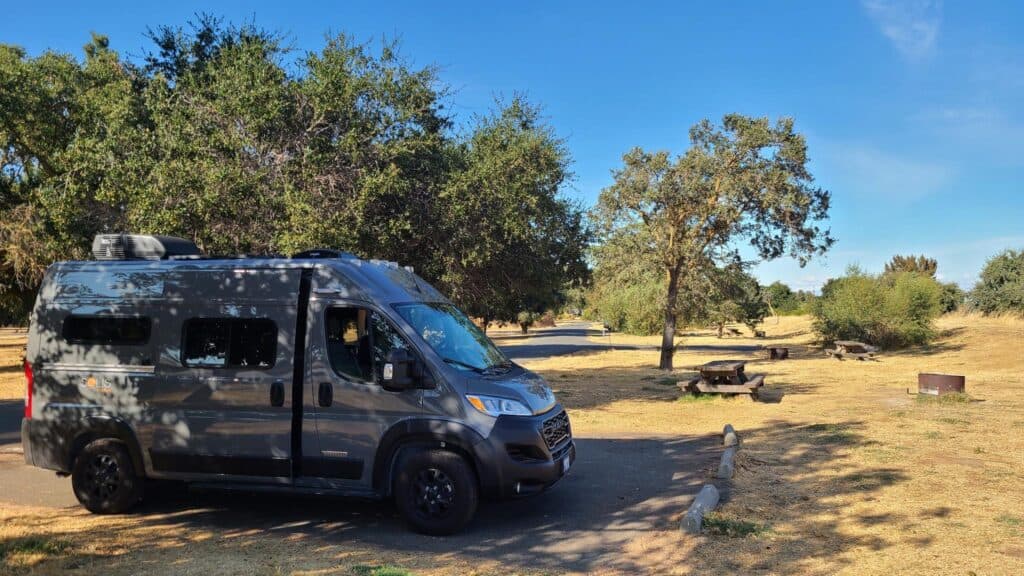 Our gray van in the oak tree shade of a Willow Campground site.