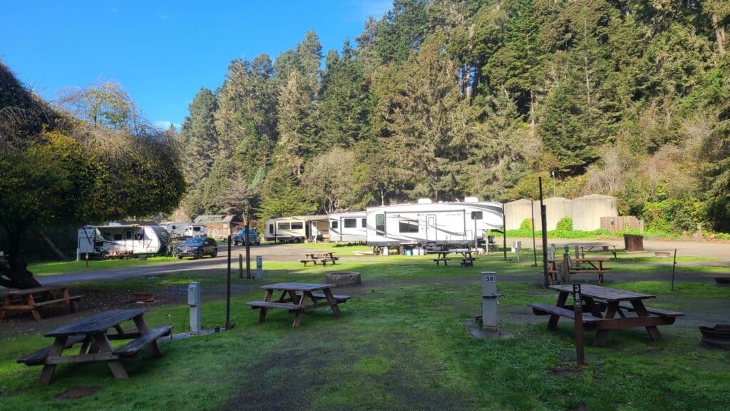 looking out at grassy campsites with two picnic tables and trailers.