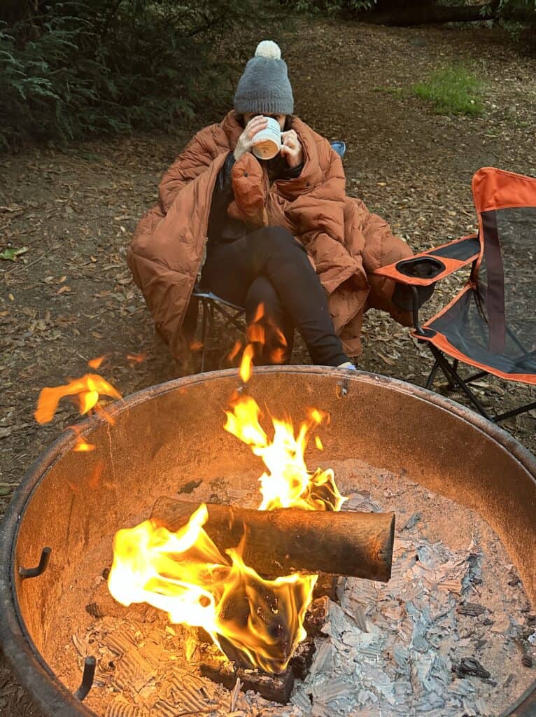 down quilt being warn around a campfire