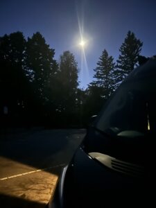 my van at night looking over the hood at the bright moon