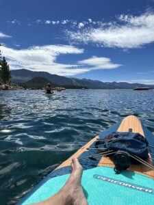 front of a paddle board looking across the water to the tree covered hills in the distance