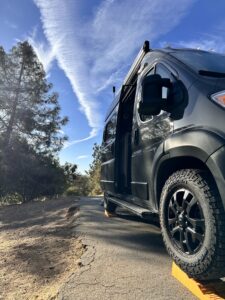 side view of the van with asphalt and dirt beside it